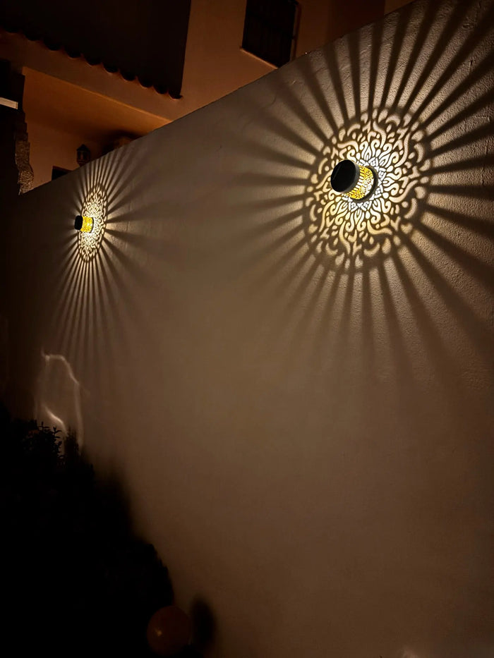 Deux lampes mandala projetant leur motif doré sur un mur, la nuit